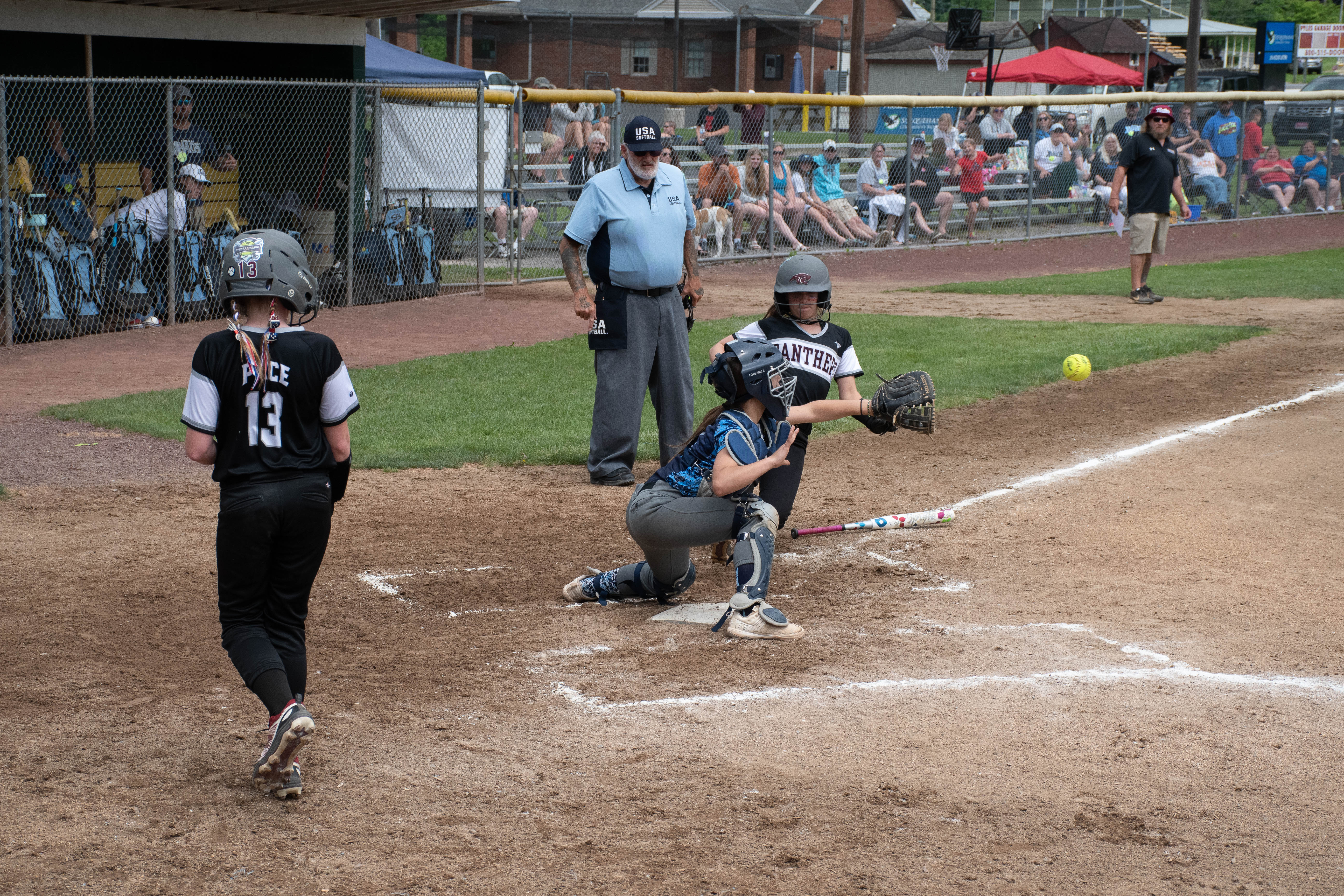 Runner sliding into home plate as catcher is about to catch ball.