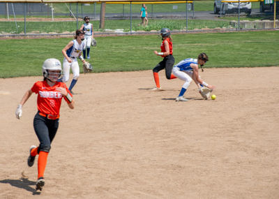 Shortstop scoops up ball as runner heads towards home plate.