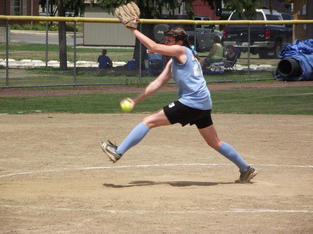 Female softball pitcher in the midst of her windup.