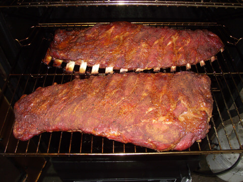 Two slabs of ribs cooking on a grill
